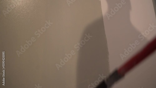 Bottom view of the wall, the repairman paints the walls with a pile roller for a perfect wall painting. Roller movement from top to bottom. High quality 4k footage
