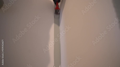 The surface of the corner is painted with paint using a brush. For uniform application of paint. Apartment renovation. The wall painting process. High quality 4k footage