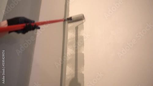 A man paints a wall with a paint roller for a perfect wall painting. Roller movement from top to bottom. Grey paint on the surface. High quality 4k footage