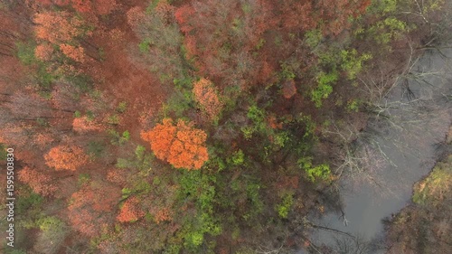 Aerial footage of forested land near Jackson Michigan on a foggy day in late autumn. The grand river snaking through colorful trees