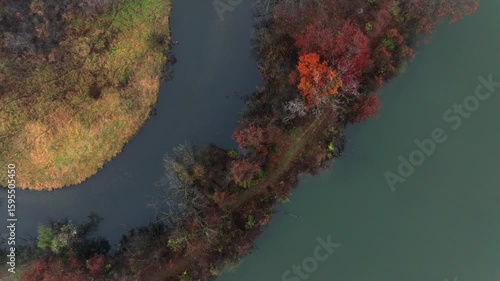 Aerial footage of forested land near Jackson Michigan on a foggy day in late autumn. The grand river snaking through colorful trees