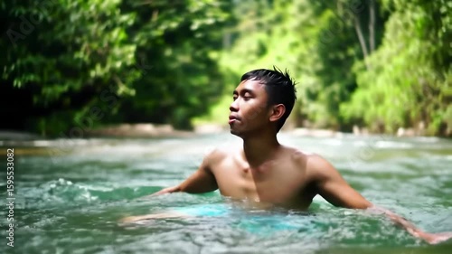 Young man relaxing in a river, surrounded by lush greenery