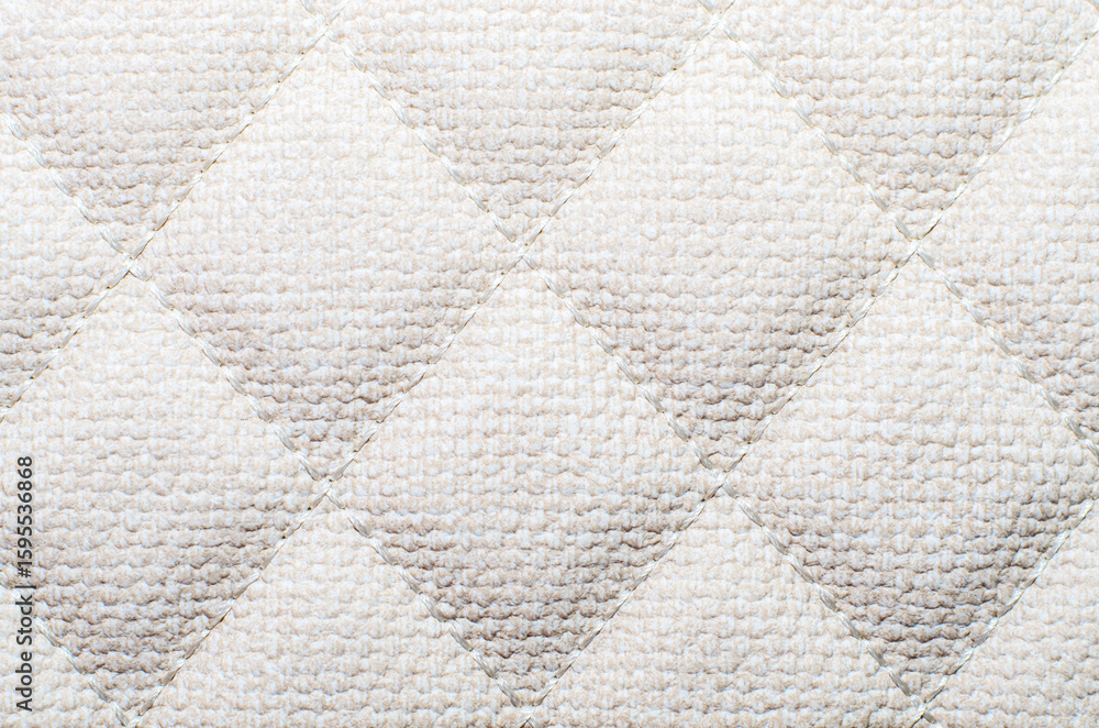 Fototapeta premium Soft light beige quilted fabric texture with diamond pattern creating cozy background