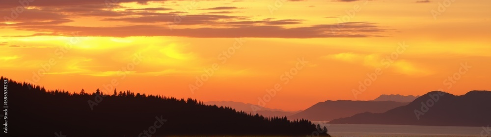 Fototapeta premium Mountains and trees are silhouetted against a sunset sky with a boat in the water banner