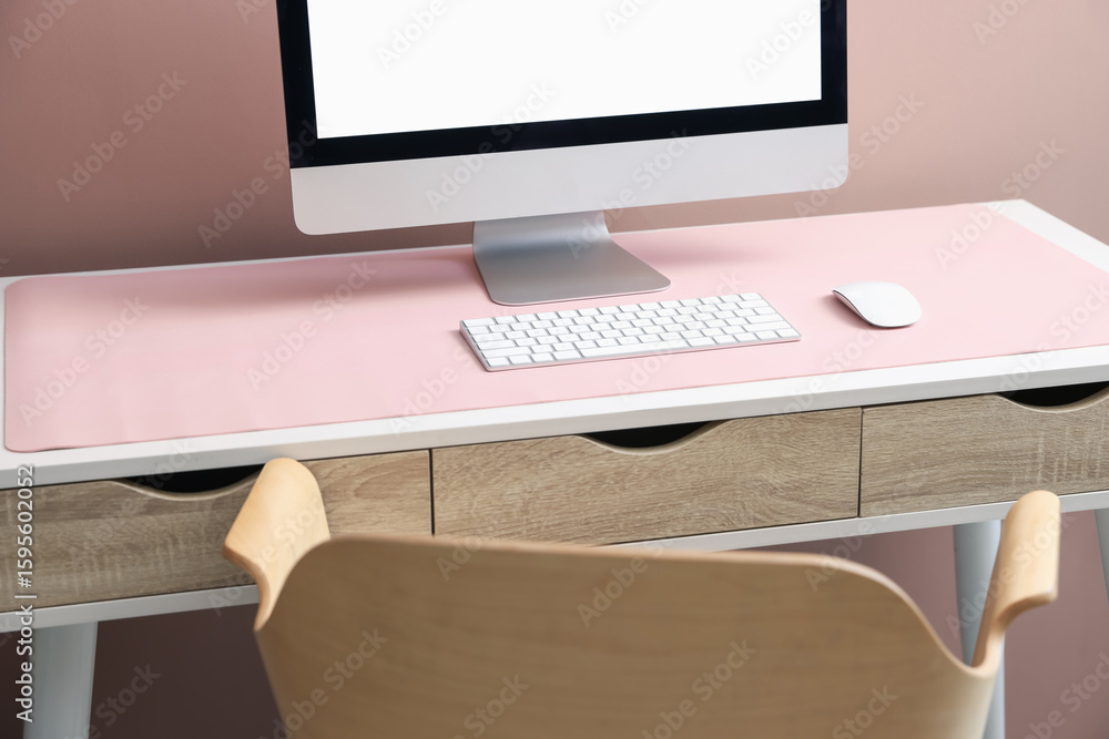 Fototapeta premium Stylish workplace with computer and pink mousepad on white table indoors. Space for text