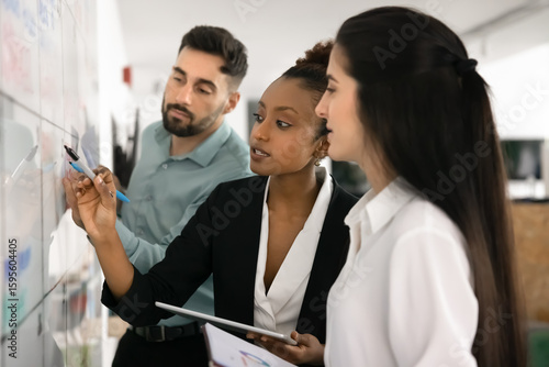 Принти на полотні Diverse workmates working together on business plan, writes on whiteboard standi
