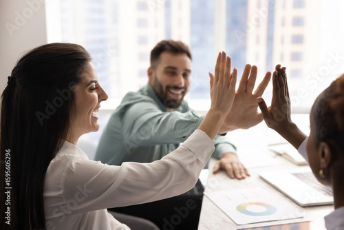 Foto Three happy teammates, staff members stacking their palms together in high-five gesture, symbolizing effective teamwork completion, celebrate shared success and collective achievement