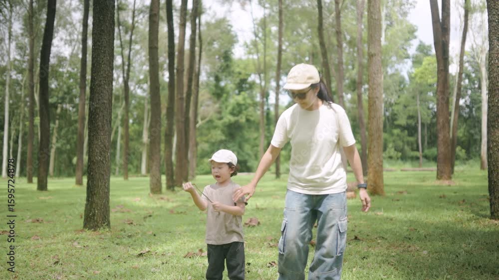 Asian mother and child walk together through a forest. The boy reacts with wonder during a peaceful and emotional family bonding moment in nature.
Asian mother and child walk together through a forest. The boy reacts with wonder during a peaceful and emotional family bonding moment in nature.