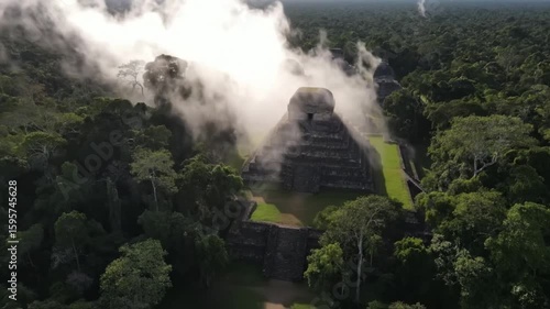 Misty morning reveals ancient mayan pyramids emerging from the dense jungle canopy in tikal, guatemala, offering a breathtaking aerial perspective