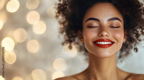 Smiling woman with curly hair against a blurred festive background, radiating joy