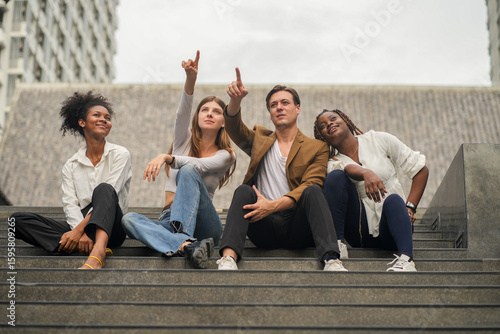 Diverse Young Friends Pointing and Sitting on City Steps