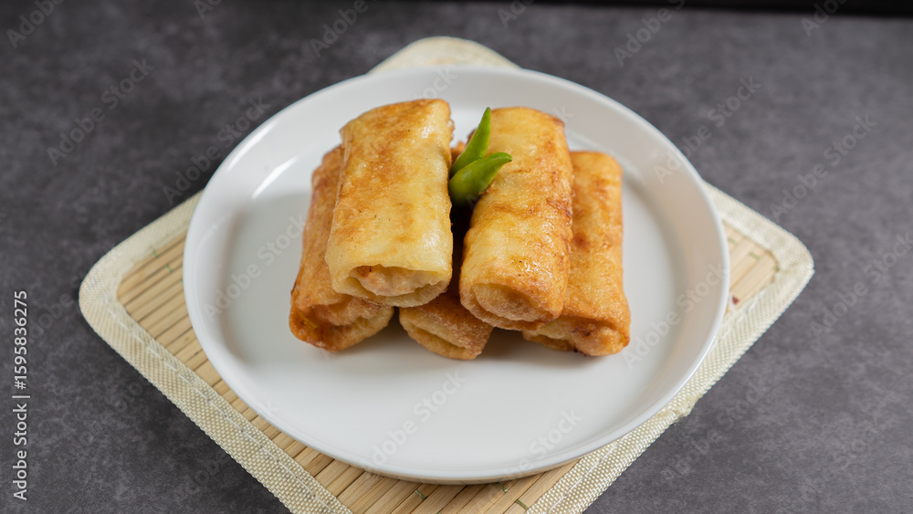Sosis Solo (Sausage Solo). Special designation for a chicken dish wrapped in an omelet and shape like sausagea. Traditional Indonesian meat snack, served on a white plate with green chili garnish. Sosis Solo (Sausage Solo). Special designation for a chicken dish wrapped in an omelet and shape like sausagea. Traditional Indonesian meat snack, served on a white plate with green chili garnish.