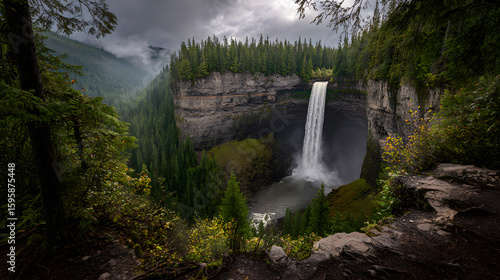 Serene waterfall cascading through a lush British Columbia rainforest with atmospheric mist. Natural Pacific Northwest beauty.