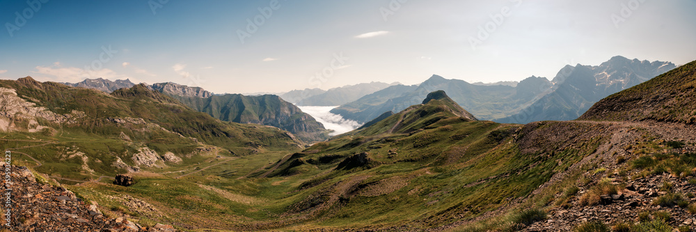 Fototapeta premium Panoramic view of the snow capped mountains of the French Pyrenees with mist hanging in the Gavarnie valley viewed from the Col de Tente