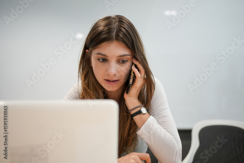 Stressed Businesswoman Talking on Phone While Working on Computer