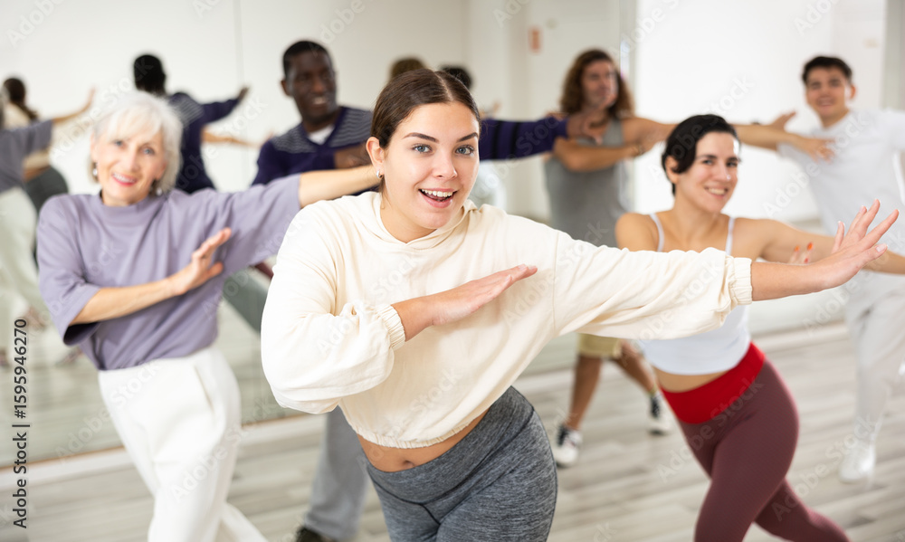 Obraz premium Portrait of cheerful young girl enjoying active dancing during group training in dance studio..