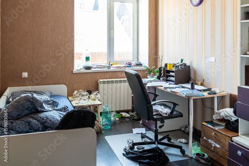 Clutter mess trash and dirt in a 15-16 year old teenage boy's room with scattered belongings, laundry and textbooks, untidy bed