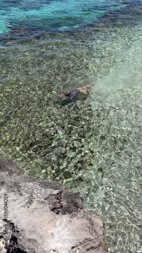 Person swimming in the ocean, top view, vertical