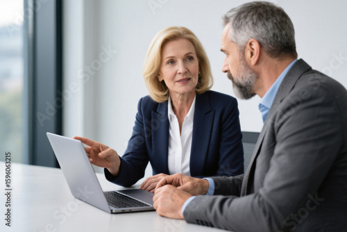 Mature business woman and man discussing project at office desk
