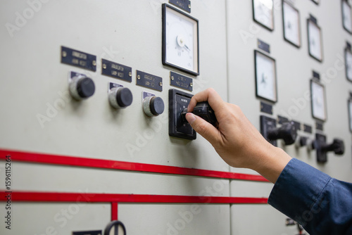 Foto Power station control room engineer adjusting switch on electrical panel with me