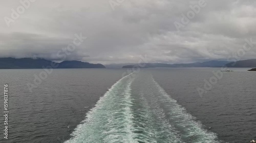 Serene Waterscape With Boat Wake and Overcast Sky in a Scenic Fjord