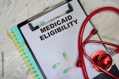 Foto Concept of Medicaid eligibility write on clipboard isolated on Wooden Table