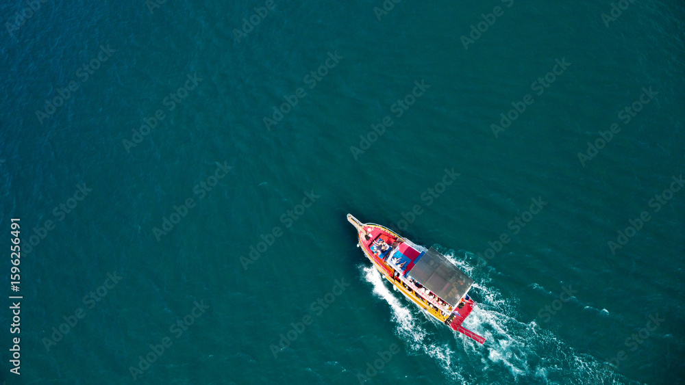 Aerial View of a Vibrant Tourist Boat on Deep Blue Sea Aerial View of a Vibrant Tourist Boat on Deep Blue Sea