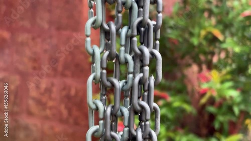 Closeup view of metal chain hanging and water droplet on spreading on it