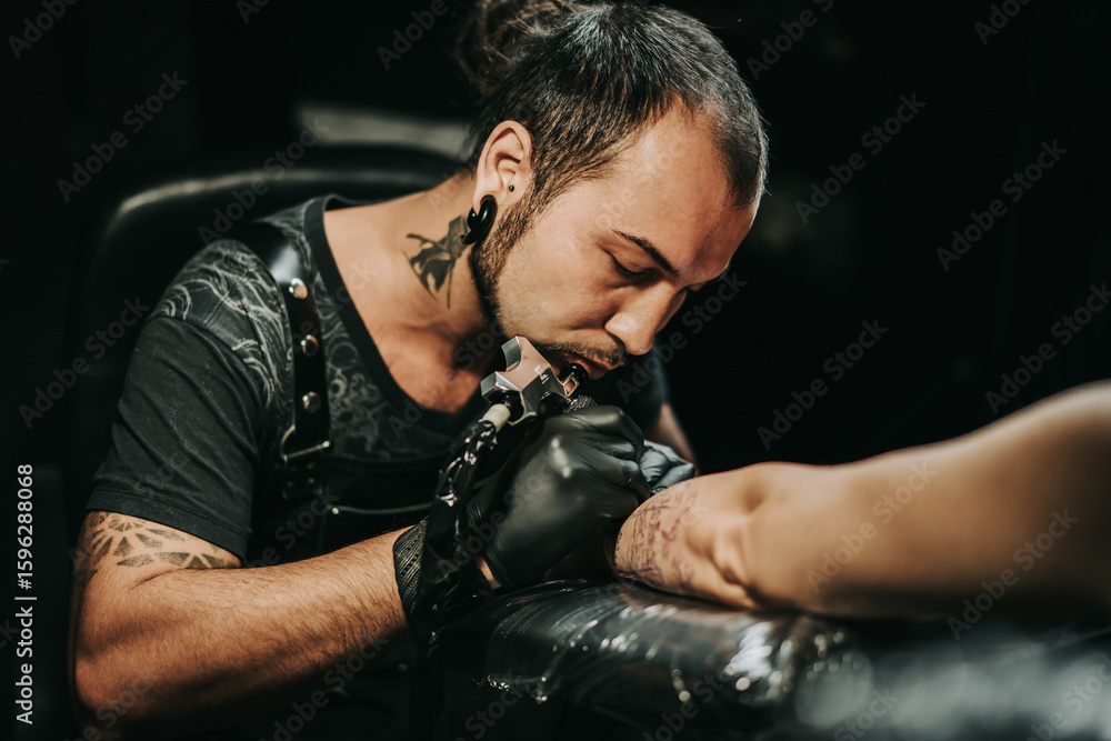 Obraz premium Man tattoo master with dreadlocks showing process creation tattoo, female body