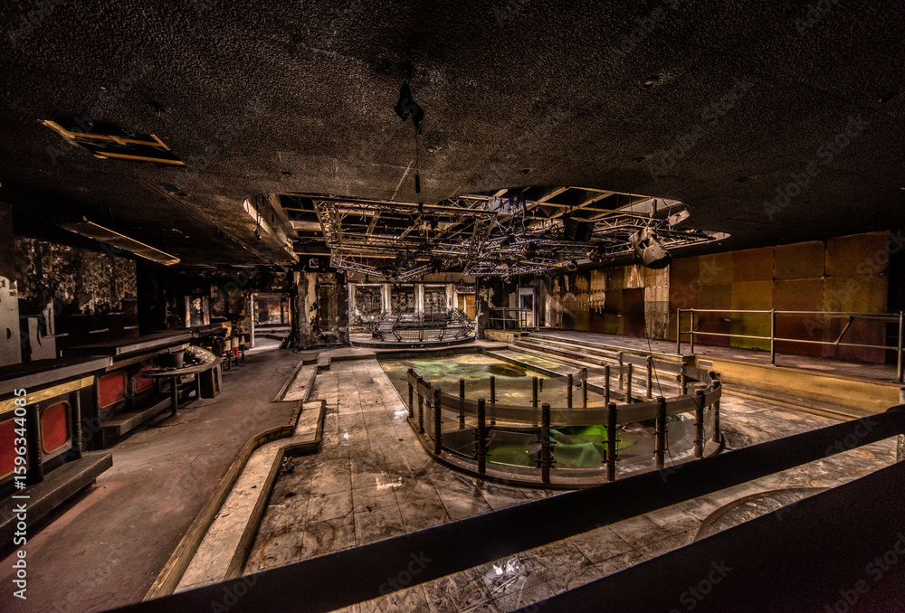 Naklejka premium Abandoned burnt-out disco interior with damaged ceiling and empty pool in a decayed urban exploration site in Germany