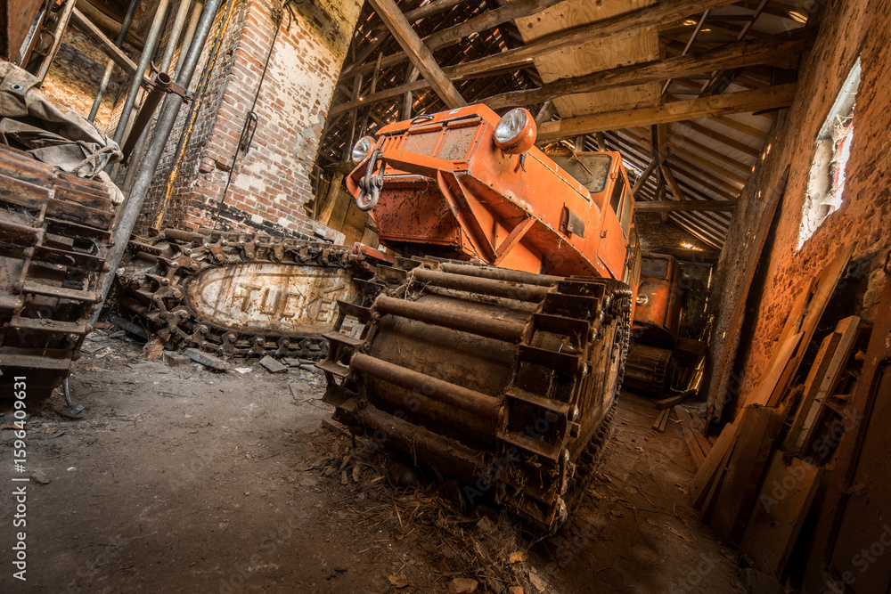 Fototapeta premium Rusty vintage tracked vehicle in abandoned barn with decayed brick walls and wooden beams