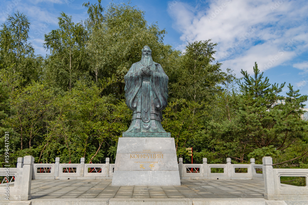 Obraz premium A statue of Confucius stands majestically in the serene Huamin Chinese Park in Moscow, surrounded by lush greenery and a peaceful atmosphere