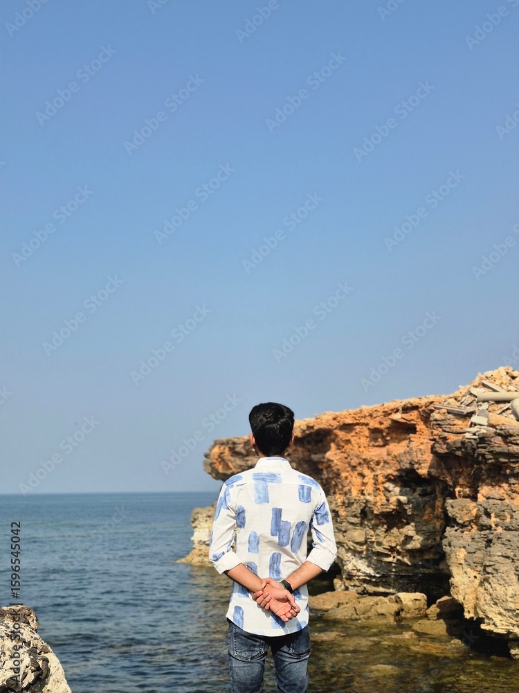 Fototapeta premium Young Man Enjoying Sea View from Cliff Edge