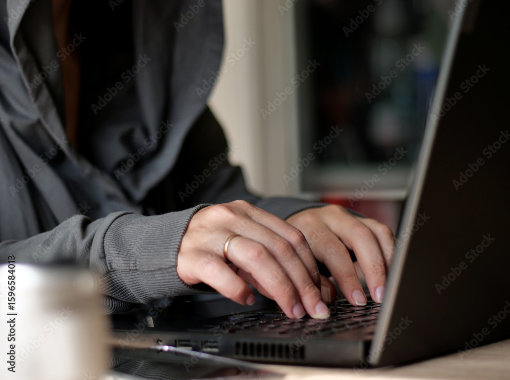 Close-up of Hooded Figure's Hands Typing on Laptop Keyboard, Focused Digital Work. Close-up of Hooded Figure's Hands Typing on Laptop Keyboard, Focused Digital Work.