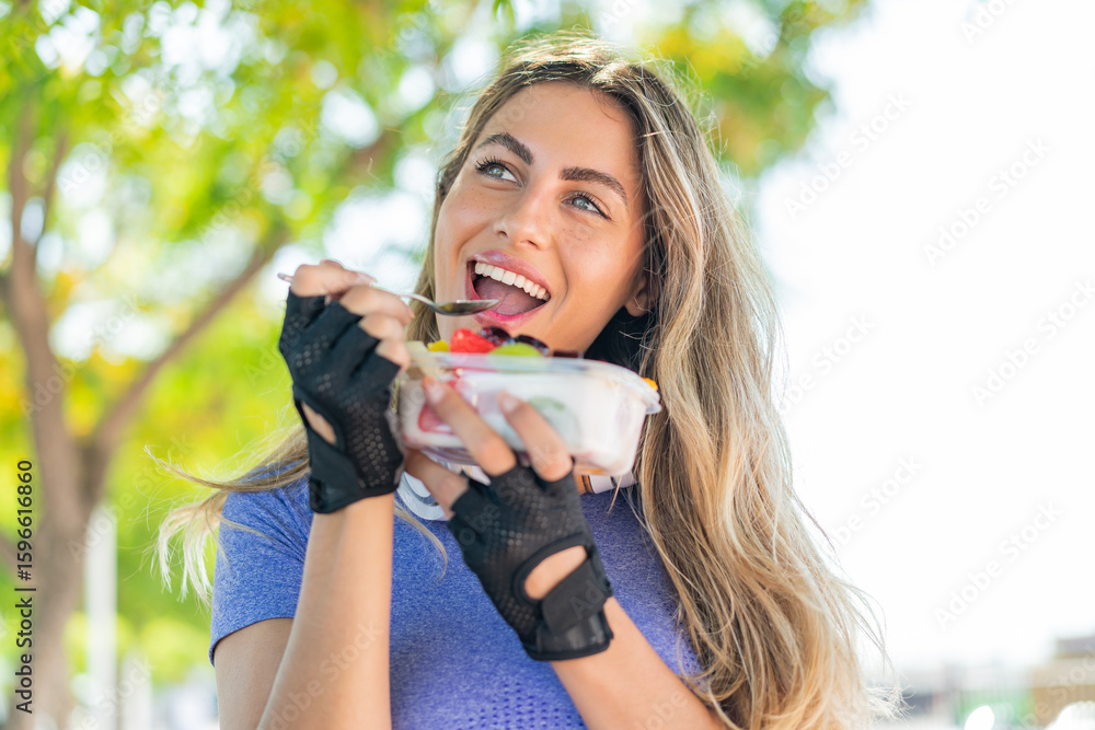 Young blonde woman holding a bowl of fruit at outdoors Young blonde woman holding a bowl of fruit at outdoors