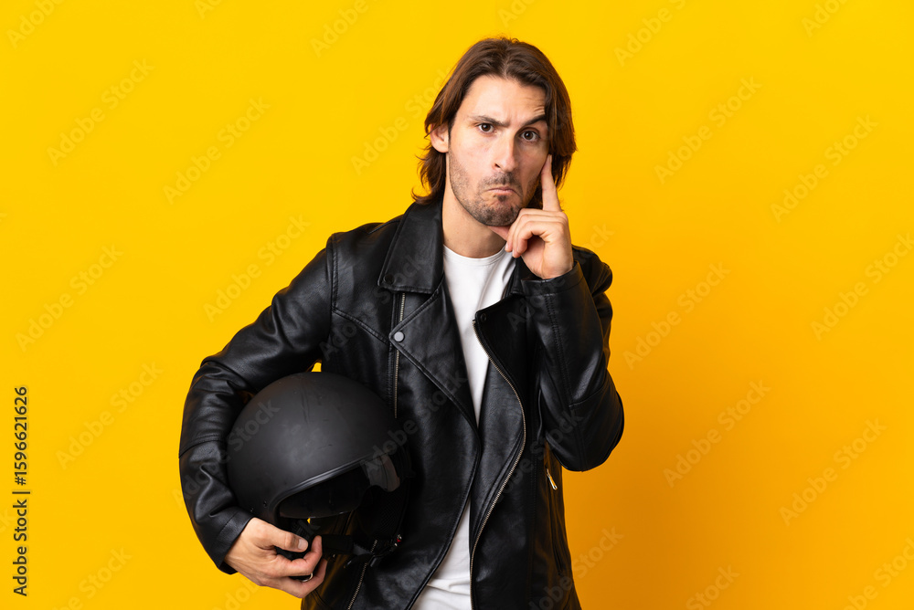 Fototapeta premium Man with a motorcycle helmet isolated on yellow background thinking an idea