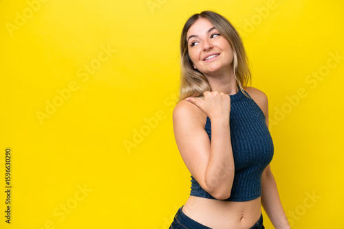 Фотография Young Rumanian woman isolated on yellow background pointing to the side to prese