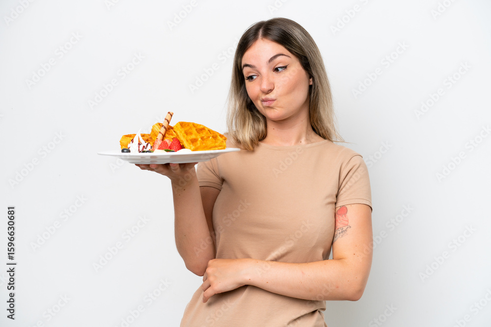 Young Rumanian woman holding waffles isolated on white background with sad expression Young Rumanian woman holding waffles isolated on white background with sad expression