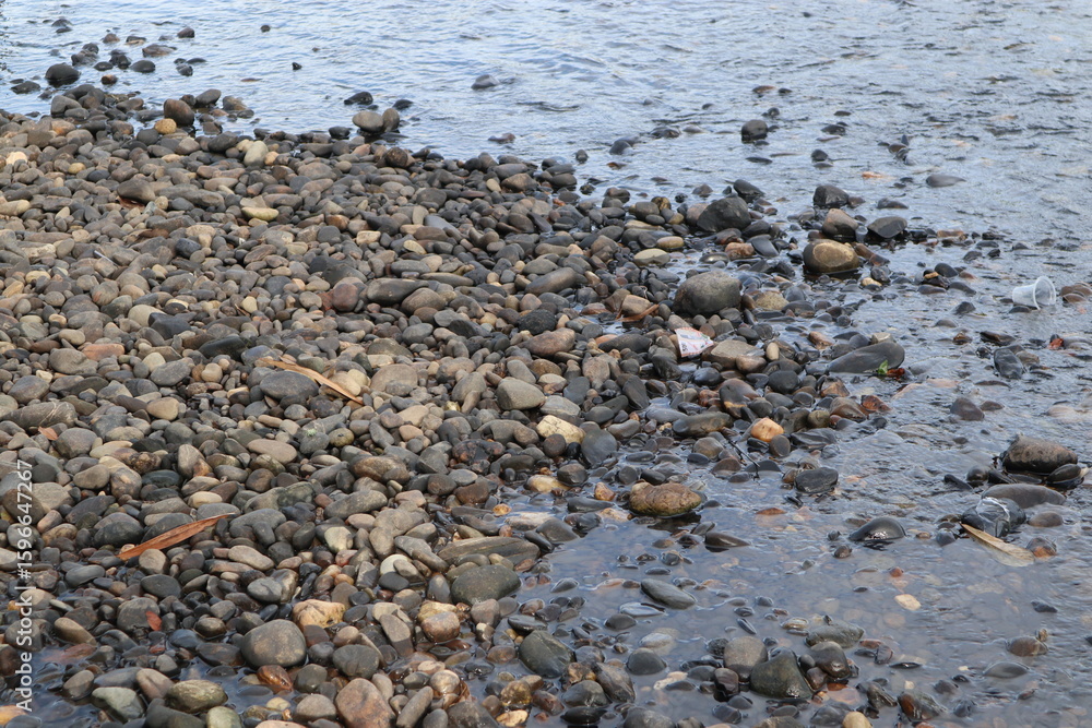 A Natural Coastal Scene Depicting Water Interacting with Rocks and Pebbles on a Shoreline A Natural Coastal Scene Depicting Water Interacting with Rocks and Pebbles on a Shoreline