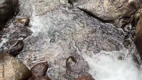 Clear mountain river water flows swiftly between large rocks, top view. Clear mountain river water. The water flows in waves. Splash of river water. Natural river views in the countryside.