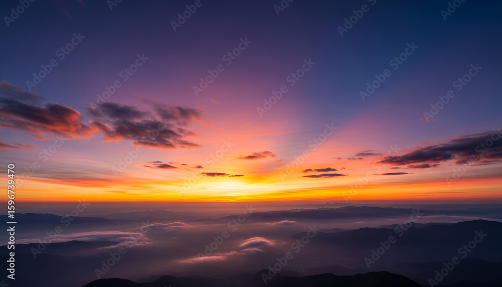 Fototapeta premium Majestic mountain silhouettes lie beneath a multicolored sky, where clouds absorb the last light of the day, creating a peaceful and poetic scene.