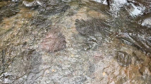 Clear mountain river water flows swiftly between large rocks, top view. Clear mountain river water. The water flows in waves. Splash of river water. Natural river views in the countryside.