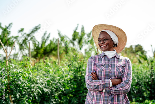 Happy Female Farmer in Sun Hat Standing in Green Field
