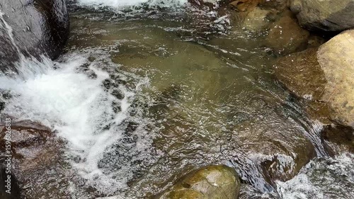 Beautiful mountain river water flows over rocks in pristine nature. A river cascading over rocks. Refreshing cold river water in a serene forest landscape with sunlight. Beautiful lansdscape. 