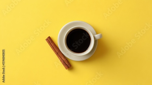 Coffee cup with cinnamon stick on vibrant yellow background