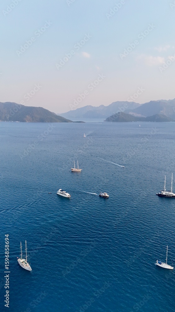 Obraz premium Sunset coastal city. Boats coastal town. Coastal mountain landscape, sea resort yachts, golden hour