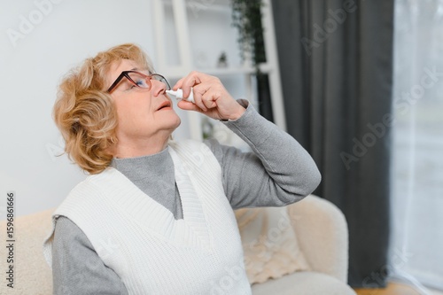 Canvas Print Senior women feeling sick, using nasal spray to help with congestion, stuffiness