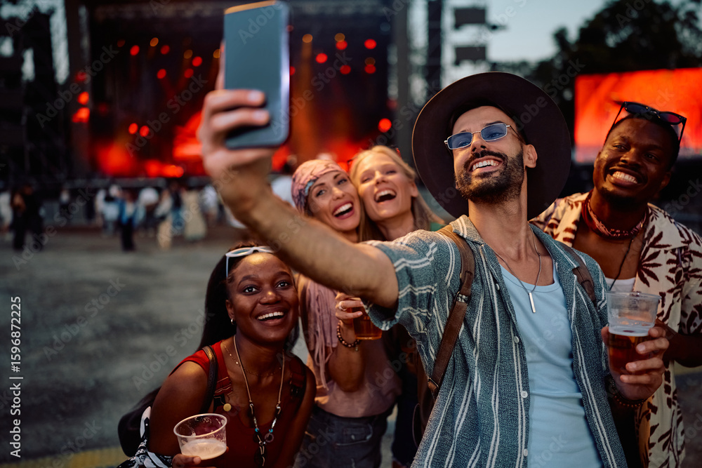 Fototapeta premium Happy festival goers talking selfie in front of music stage during summer festival.