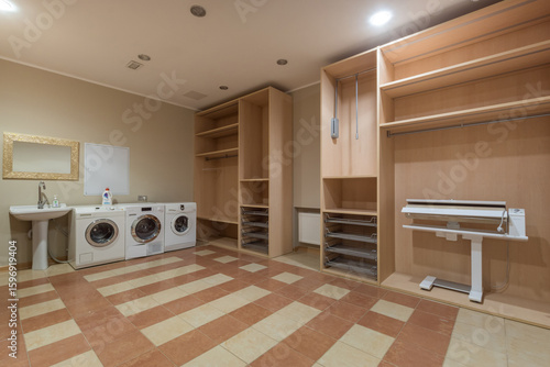 Canvastavla A functional laundry room with two washing machines, a working area, and ample storage space