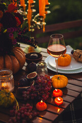 Garden romantic party outside with wine, cheese, fruits. Field or meadow, family event, cozy autumn atmosphere, fall vibes. Wooden furniture, pumpkin with flowers as centrepiece, fresh red dahlia